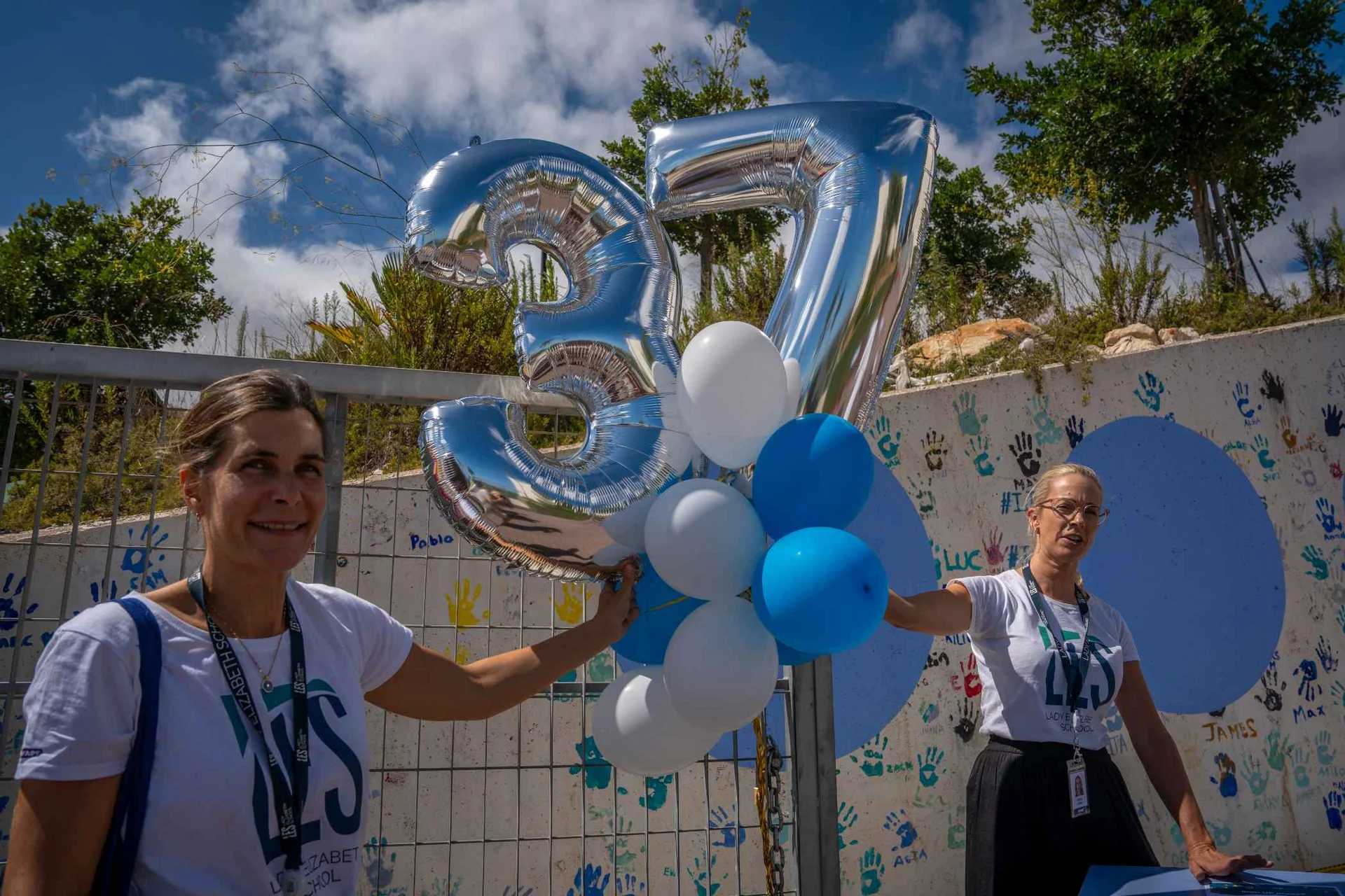 Two teachers hold balloons for 37th school anniversary