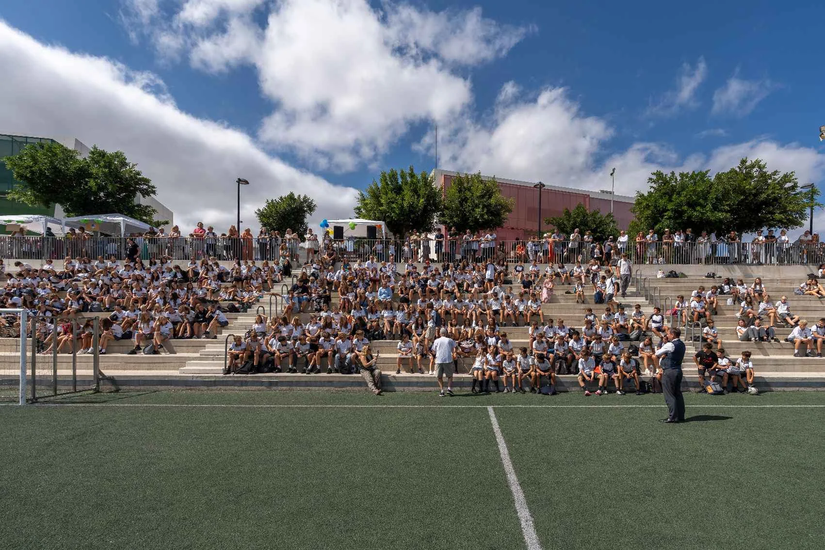 School students sitting in the stands of a field 