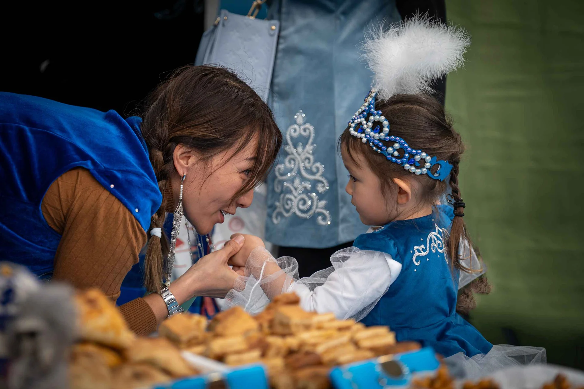 A woman kissing hand of a baby girl dressed like a princess