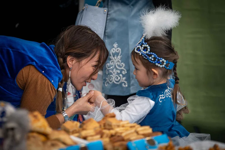 A woman kissing hand of a baby girl dressed like a princess