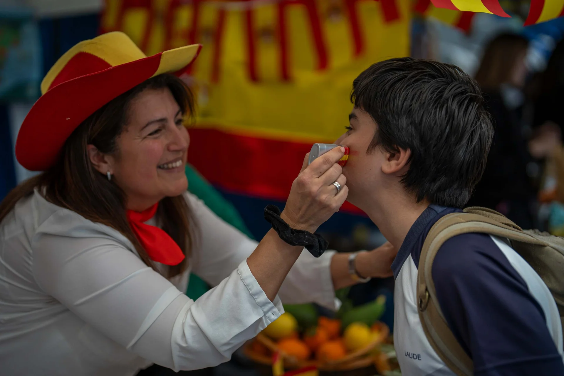 A mum painting with red and yellow a student's face