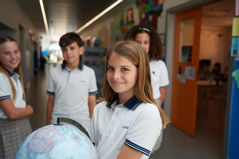 Student smiling and holding a globe 