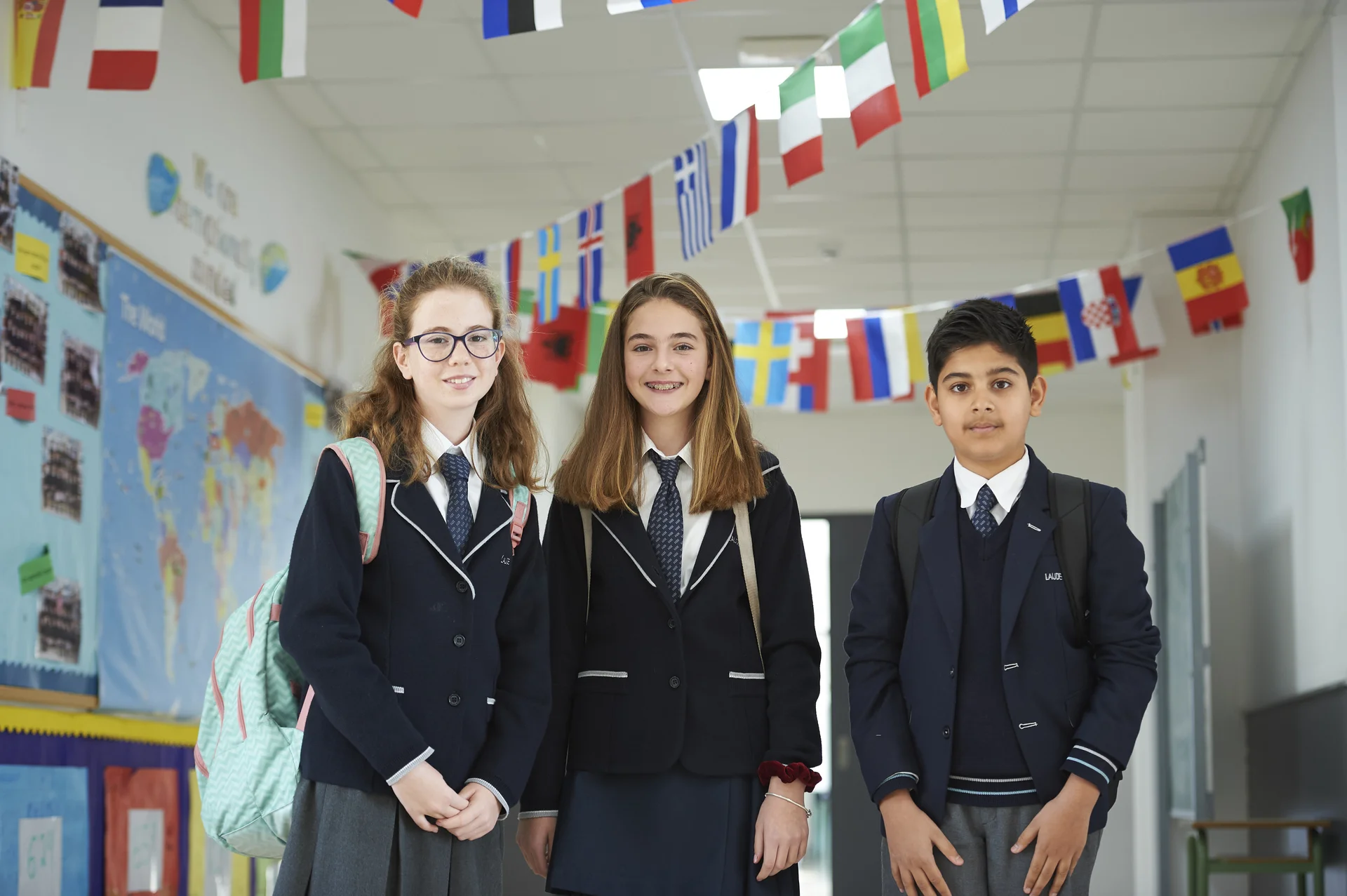 Three students in uniform posing and smiling