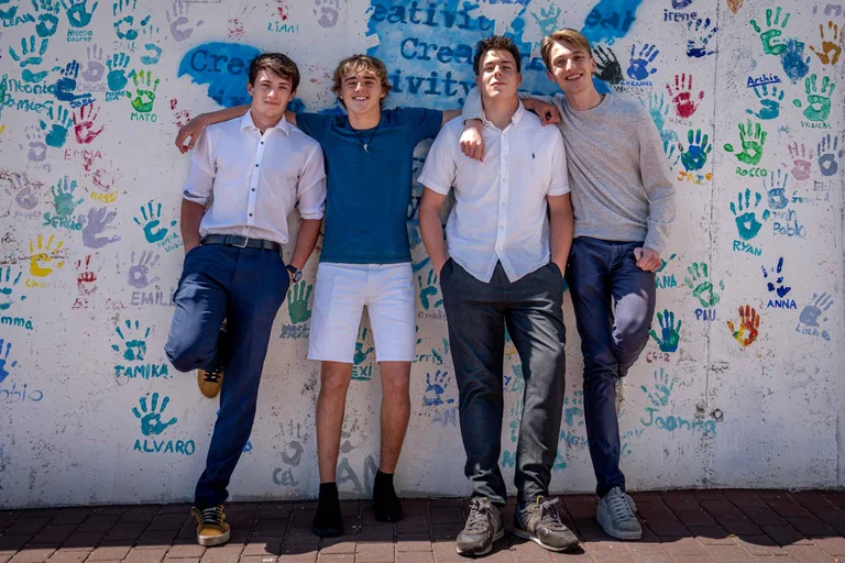 Four students in front of a wall 